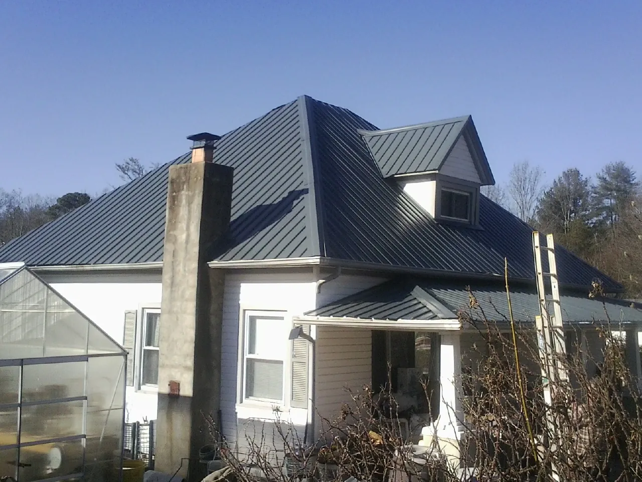 Dark blue standing seam metal roof on a white farmhouse with dormer — Slate & Tile Roof Repair by Roofing Brothers in Goldendale