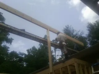 Carpenter setting a ridge beam over a new addition frame — Ice Dam Removal by Roofing Brothers in Goldendale