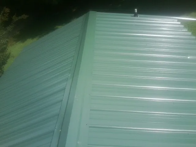 New green metal panels meeting at the ridge of a roof — Flat Roof Repair work by our crew in Goldendale