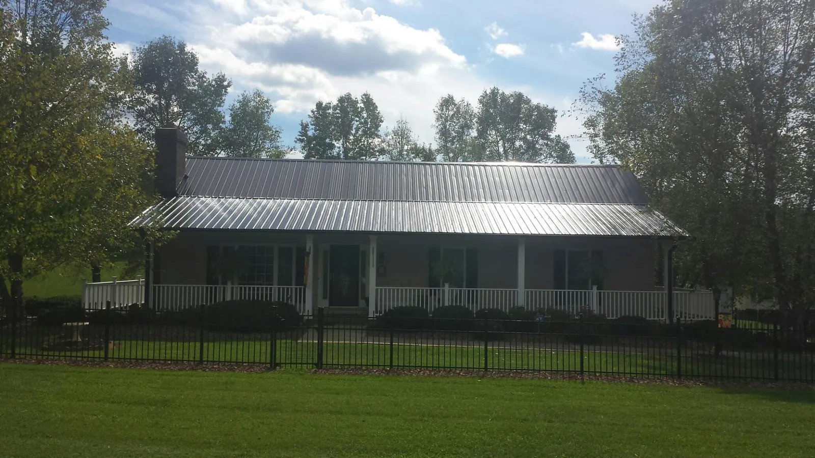 Gray metal roof on a brick ranch with a full width front porch — Gutter Guard Installation work by our crew in Goldendale