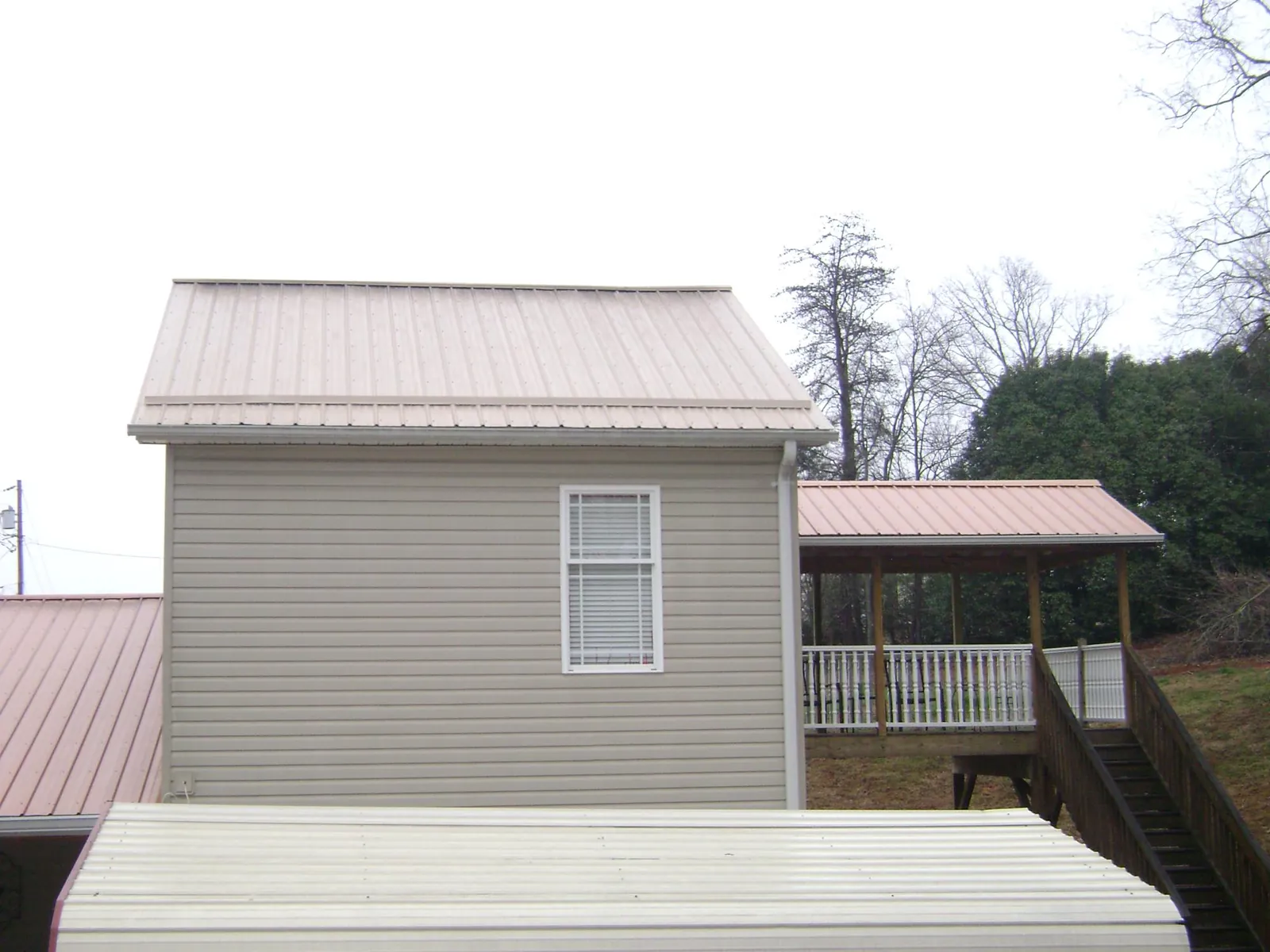 Tan metal roofs on a two story addition and attached porch, from a Roof Replacement job in Goldendale
