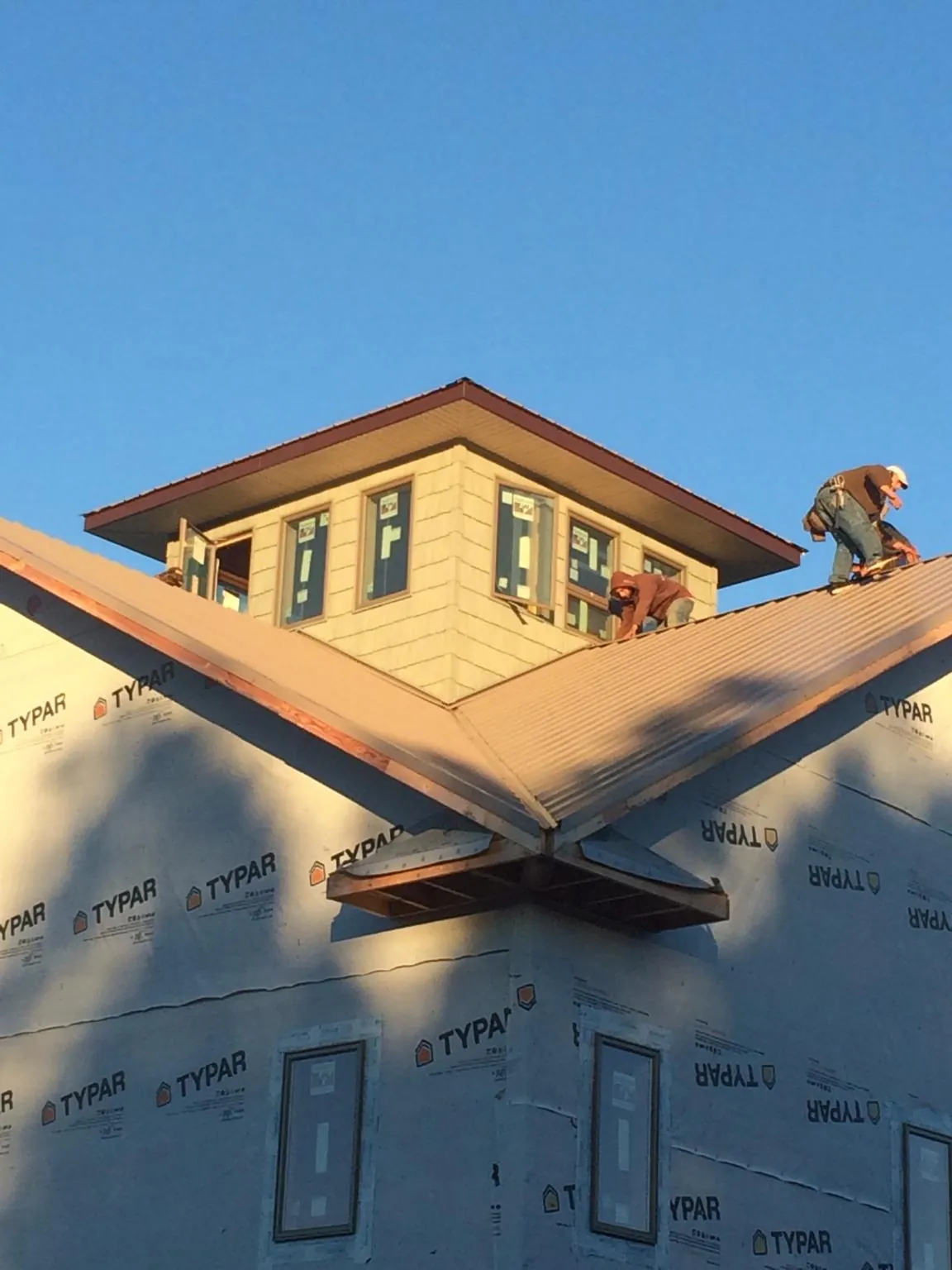 Roofers working around a rooftop cupola on a new metal roof at sunset — Roof Waterproofing in Goldendale by Roofing Brothers